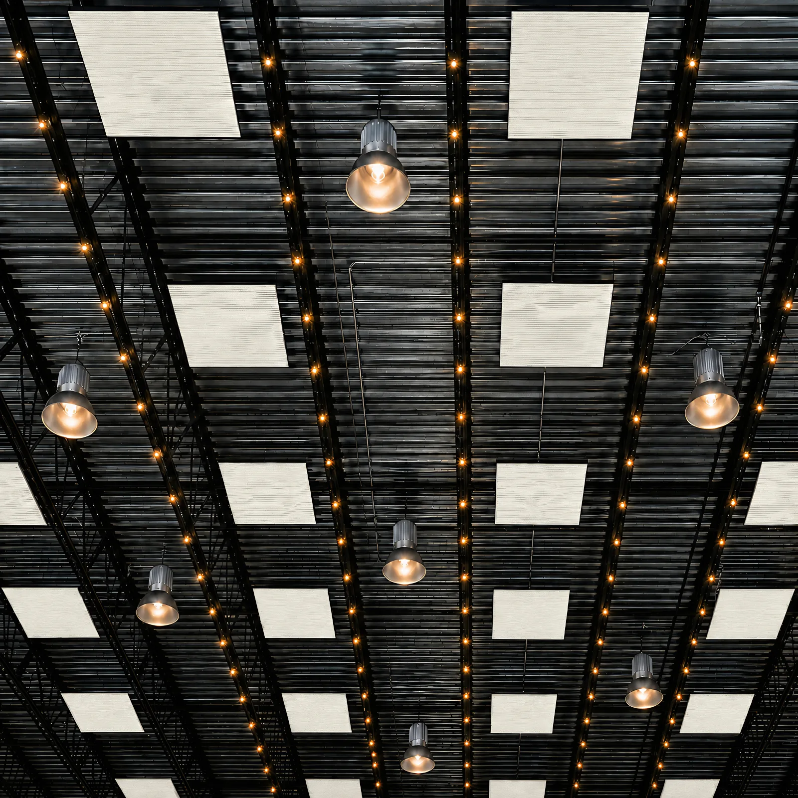 Acoustic ceiling cloud panels in Spirit off-white suspended in a grid below a black open steel deck in a warehouse