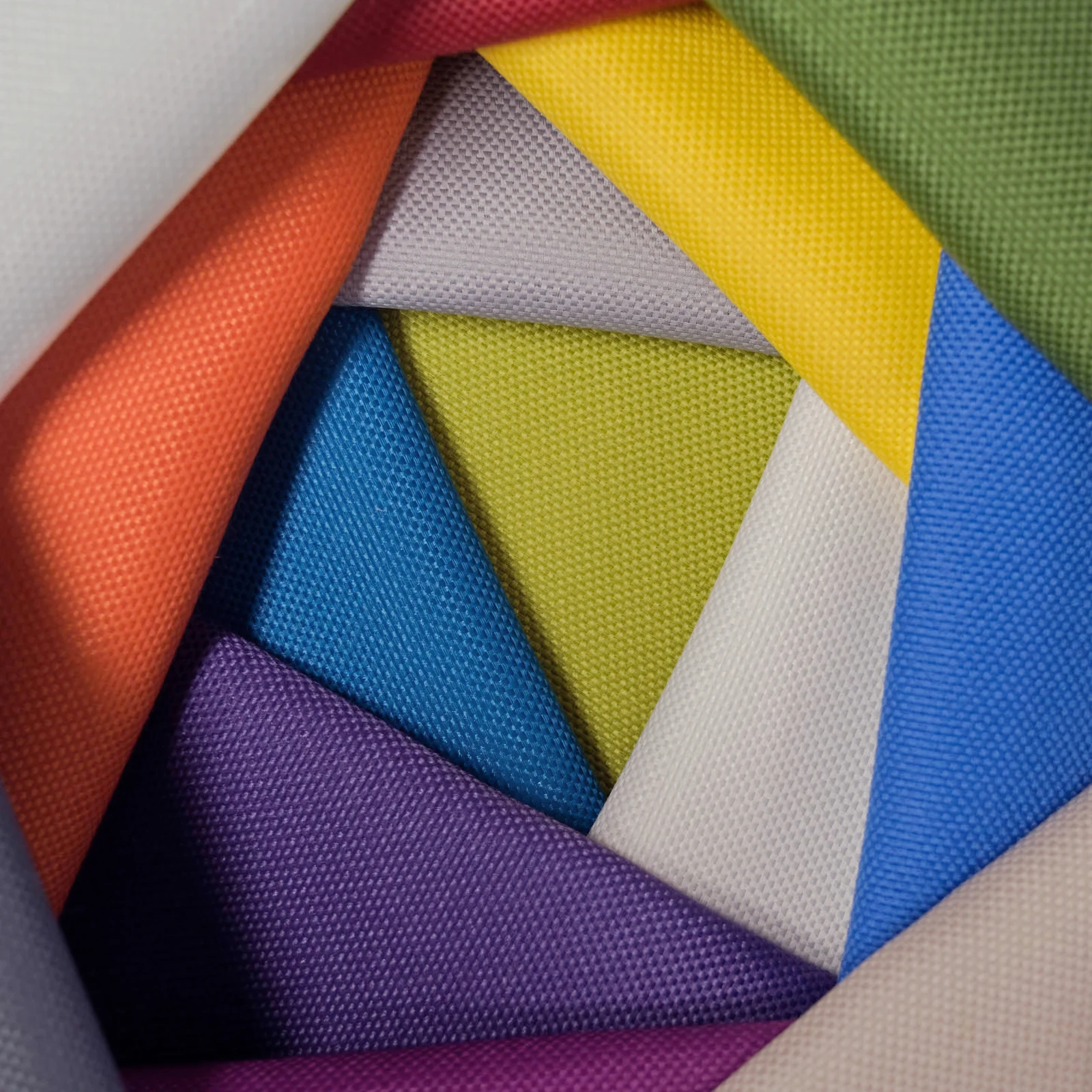 Acoustically transparent acoustic wall panel fabrics fanned out to show the weave and the range of colors available
