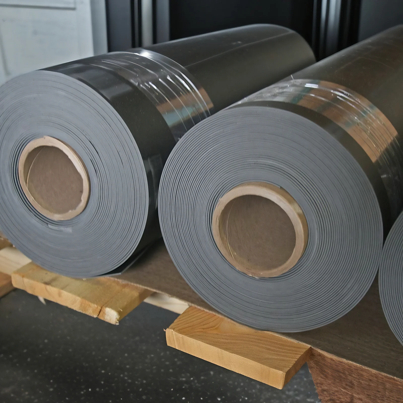Rolls of Wall Blokker Lite mass loaded vinyl stacked on pallet blocking in a warehouse